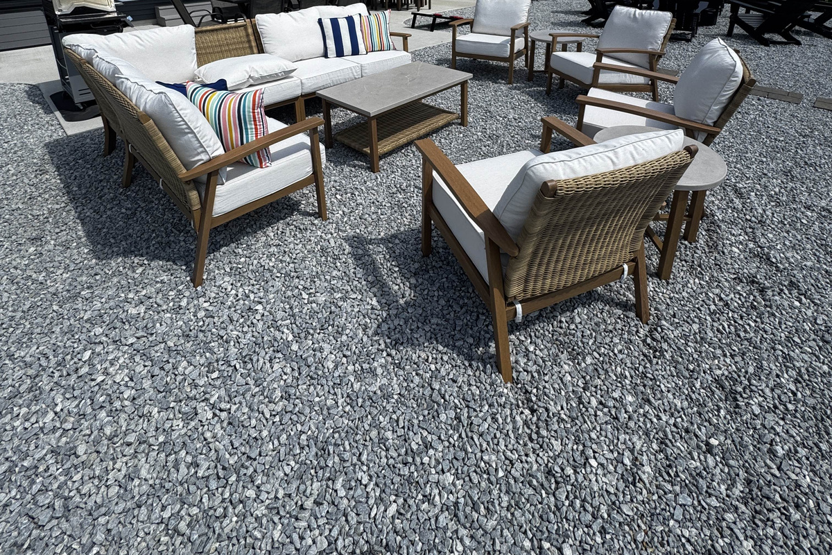 Outdoor lounge seating area with comfortable cushioned chairs and coffee table, set on a spacious gravel patio perfect for relaxing and socializing.