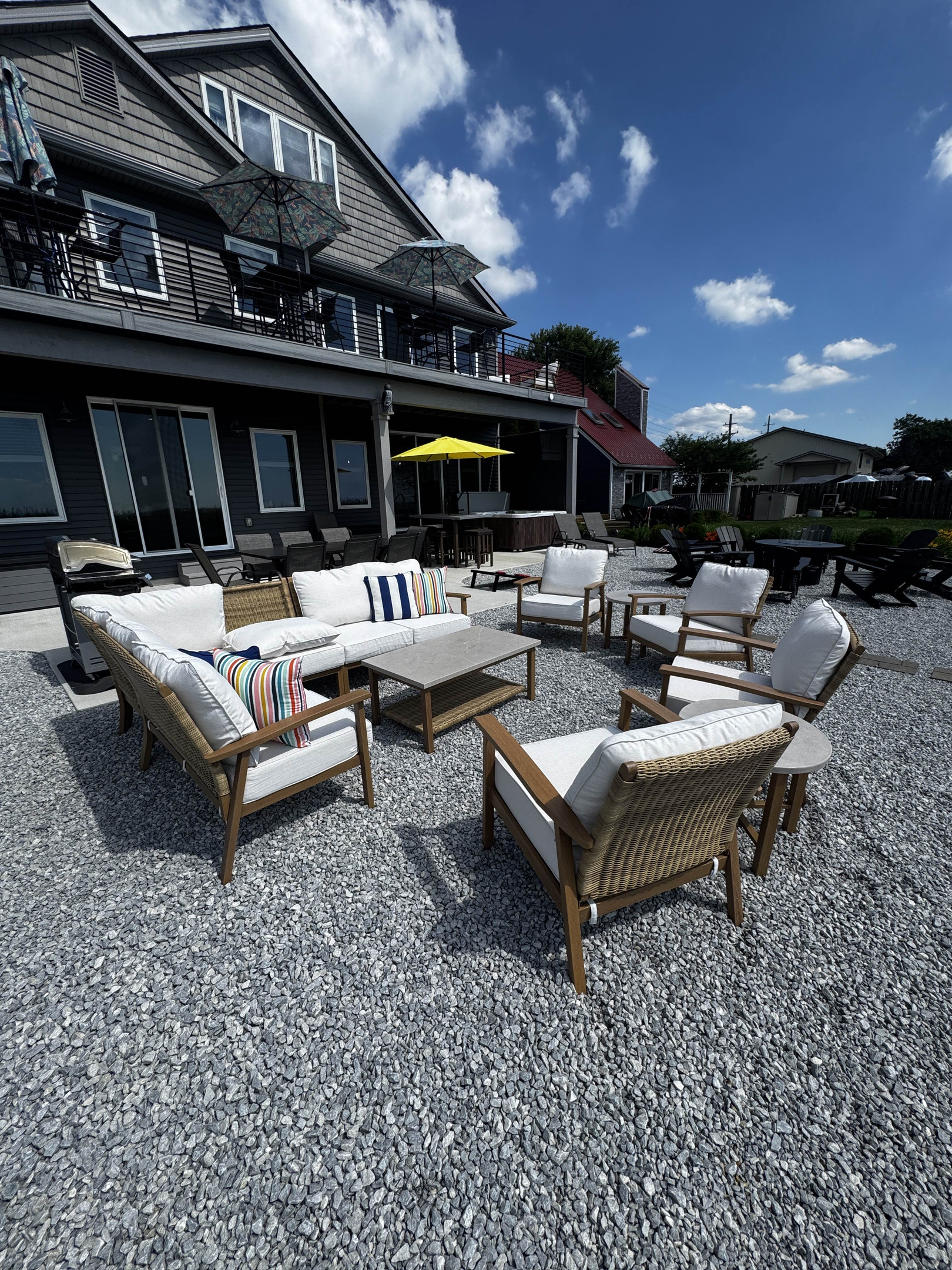 Outdoor lounge seating area with comfortable cushioned chairs and coffee table, set on a spacious gravel patio perfect for relaxing and socializing.