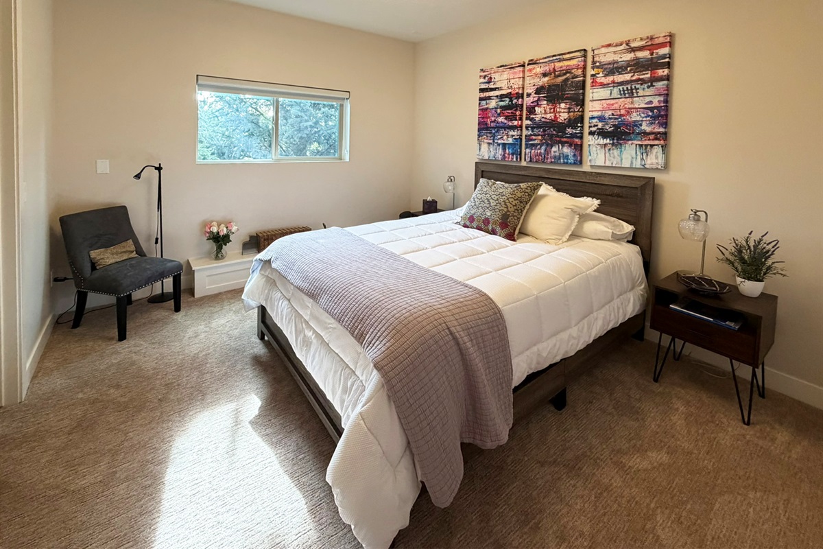 Comfortable downstairs queen bedroom featuring soft natural light, cozy furnishings, and peaceful mountain retreat vibes.