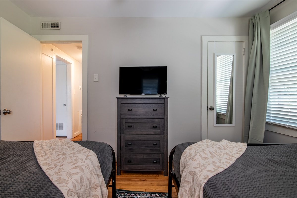 Spacious bedroom with TV and dresser, offering plenty of natural light and storage space.