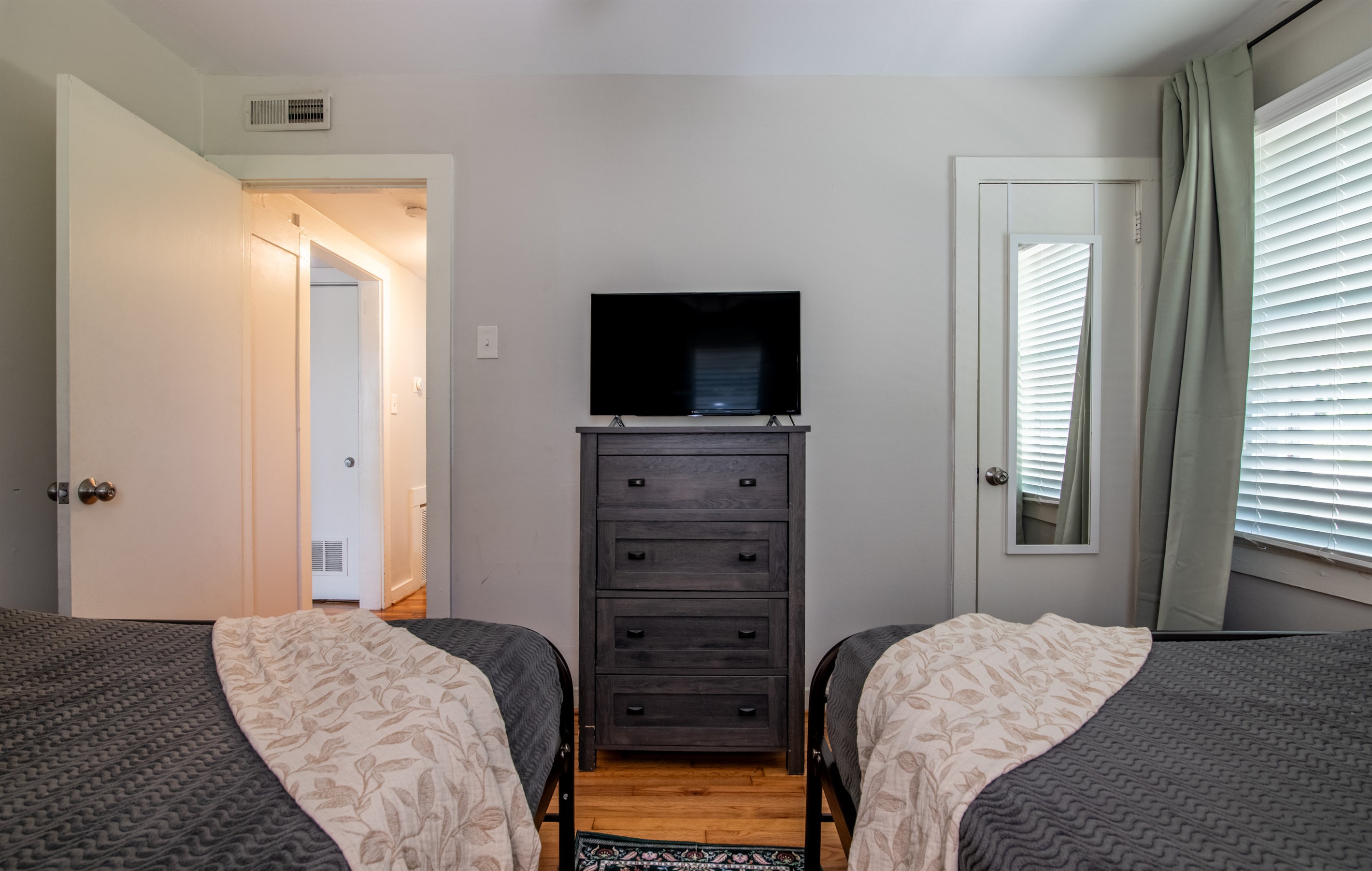 Spacious bedroom with TV and dresser, offering plenty of natural light and storage space.