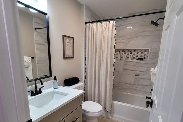 Freshly renovated and beautifully appointed, this guest bathroom features modern finishes, a tiled tub/shower combo, and all the essentials for a comfortable stay.
