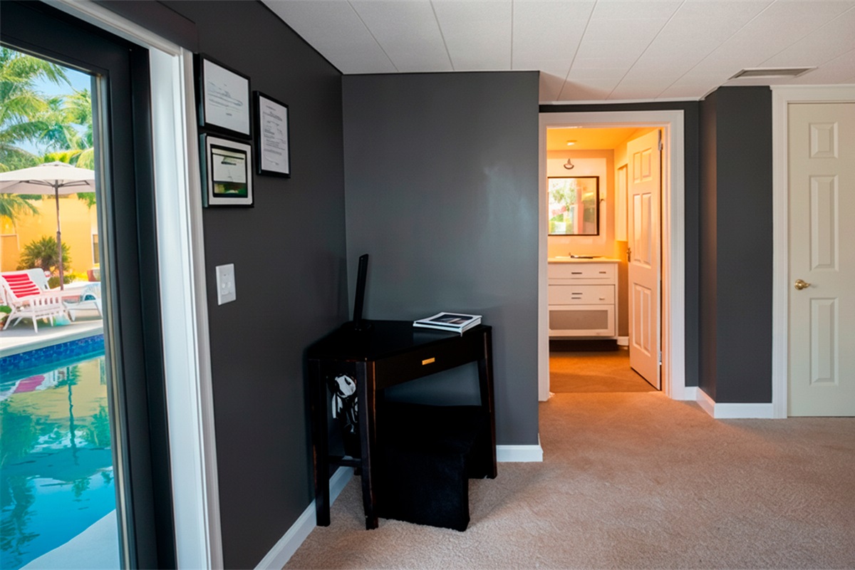 Functional interior view of The Red Room, featuring a dedicated desk, direct pool access, and a private bathroom entry.