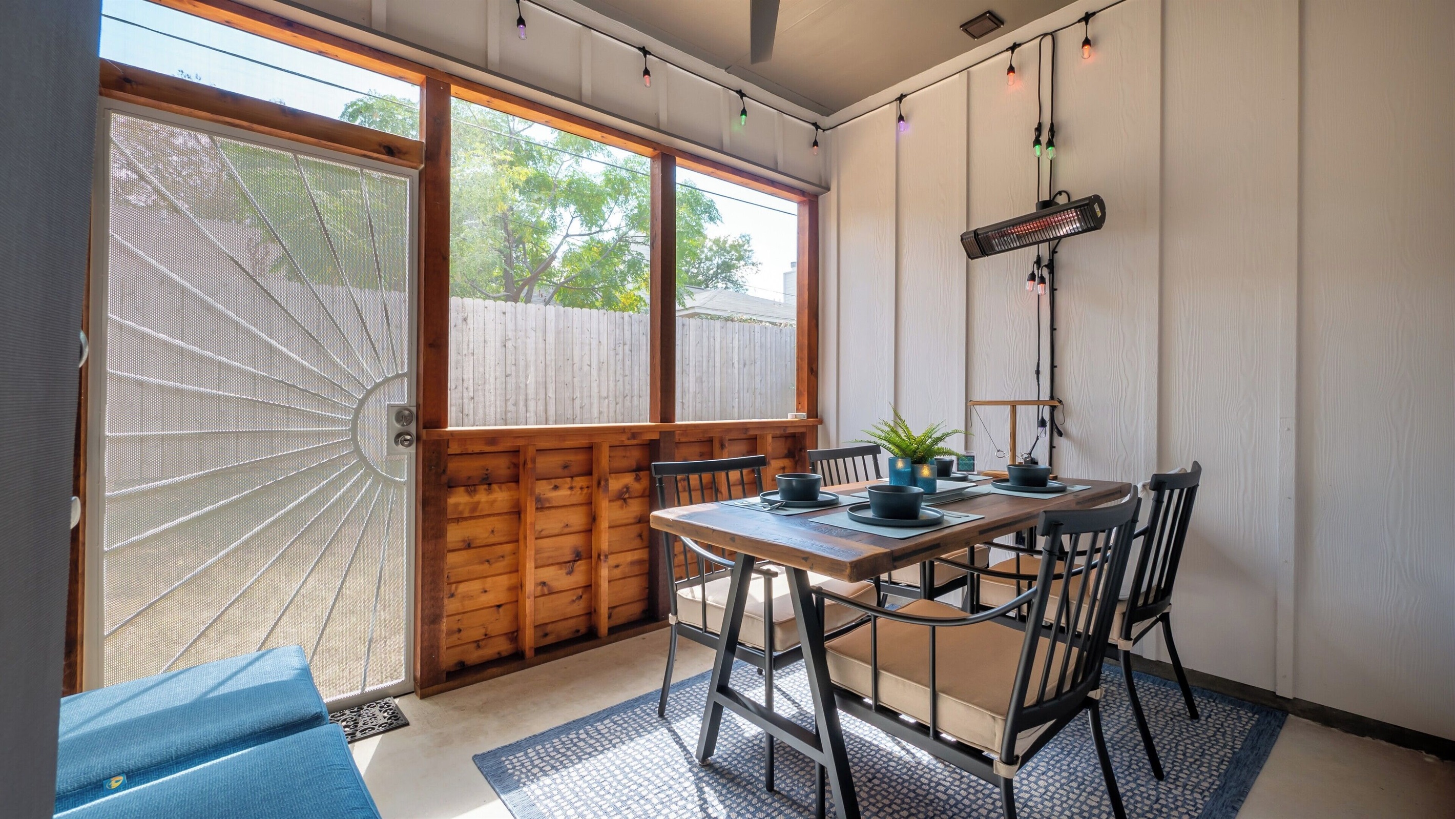 Screened-in patio with dining table, ceiling fan, heater, and hanging lights for year-round comfort