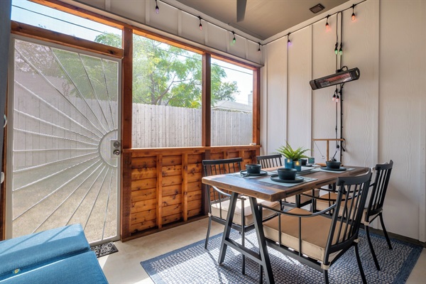 Screened-in patio with dining table, ceiling fan, heater, and hanging lights for year-round comfort
