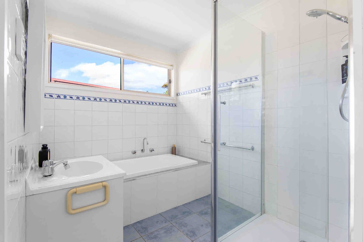 The full bathroom at Carlenes Getaway includes a separate shower, bathtub and natural light for an easy Loch Sport stay.