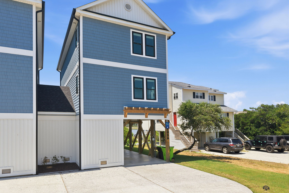 The elevated coastal home offers ample parking, a bright modern exterior, and a prime location near the beach and scenic marshes