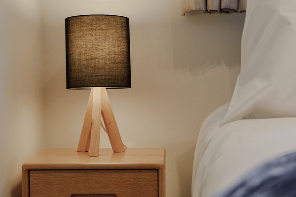 Warm bedside lamps, navy bedding and a leafy window outlook give this bedroom a calm alpine feel at Fernhill Mountain Escape.