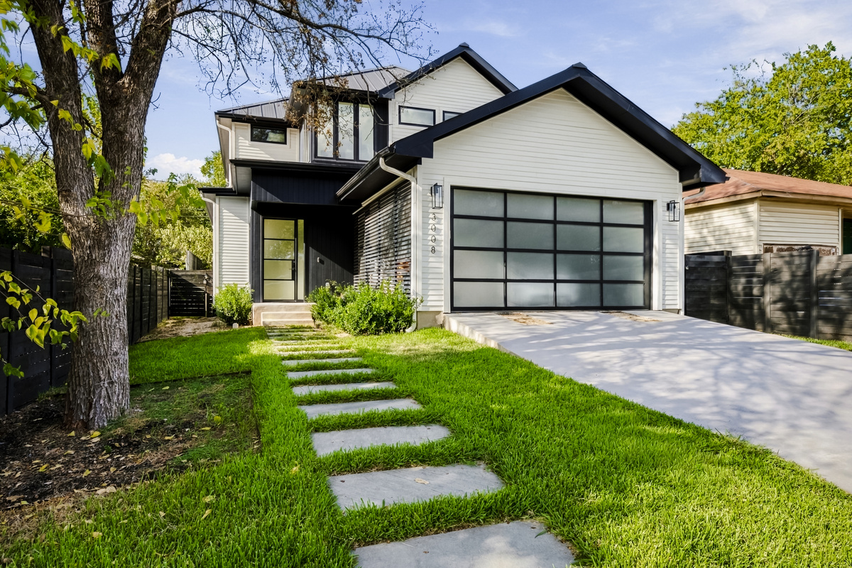 Modern black-and-white exterior with a two-car garage and stepping-stone path.