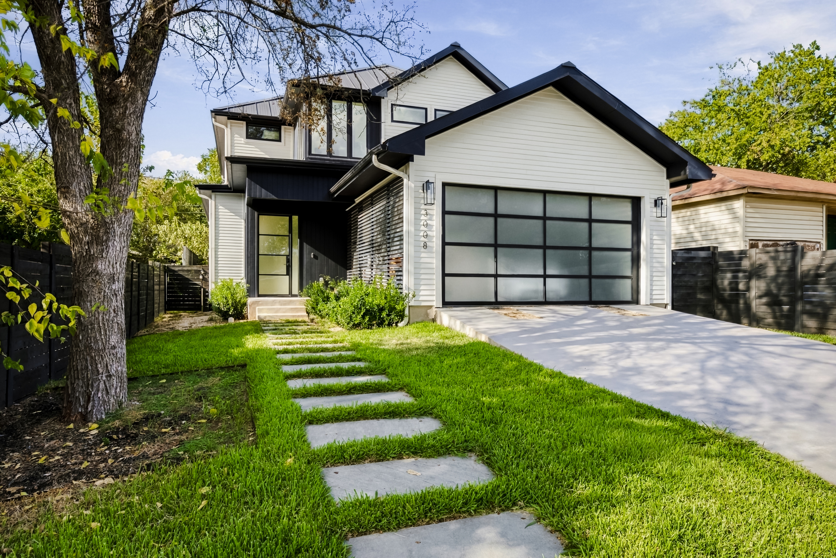 Modern black-and-white exterior with a two-car garage and stepping-stone path.