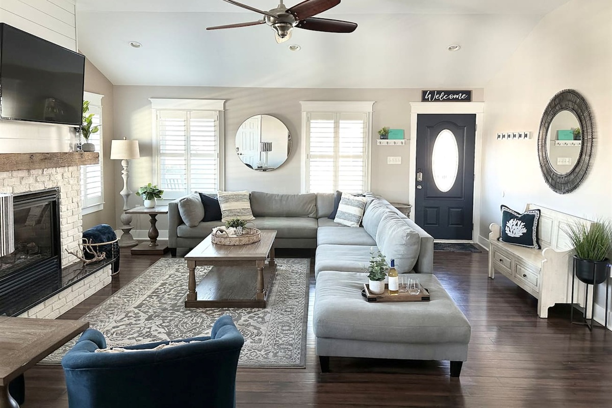 Step into our welcoming, sun-drenched living room where beachy charm meets modern comfort. With its vaulted ceilings, cozy fireplace, and sprawling sectional, it is the perfect spot for your family to gather and recharge.