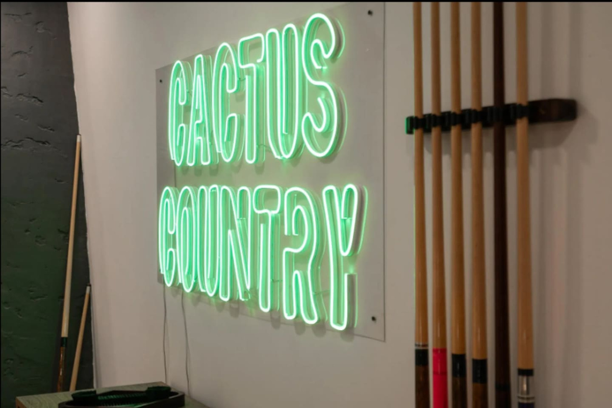 Custom neon signage and a full cue rack complete the game room's laid-back, playful vibe.
