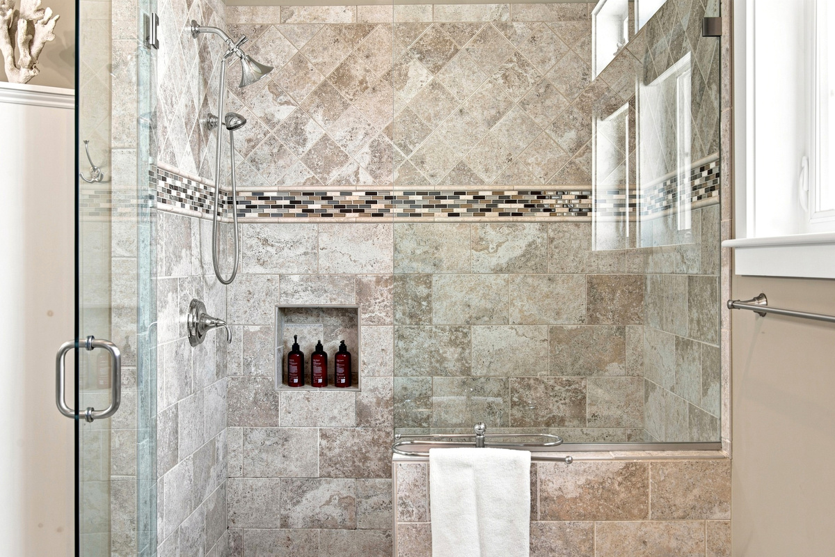 The glass-enclosed walk-in shower features detailed tilework for a clean, polished bathroom experience.