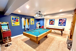 Entertainment-packed space featuring a pool table, two arcade machines, and an air hockey table for endless fun