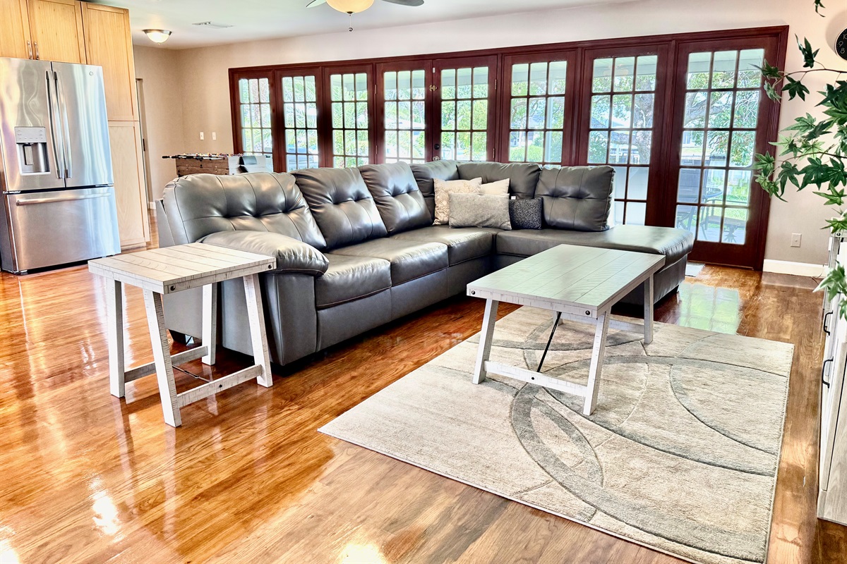This sun-drenched living room features a plush sectional, modern décor, and sleek hardwood floors—perfect for lounging in style or enjoying a cozy movie night.