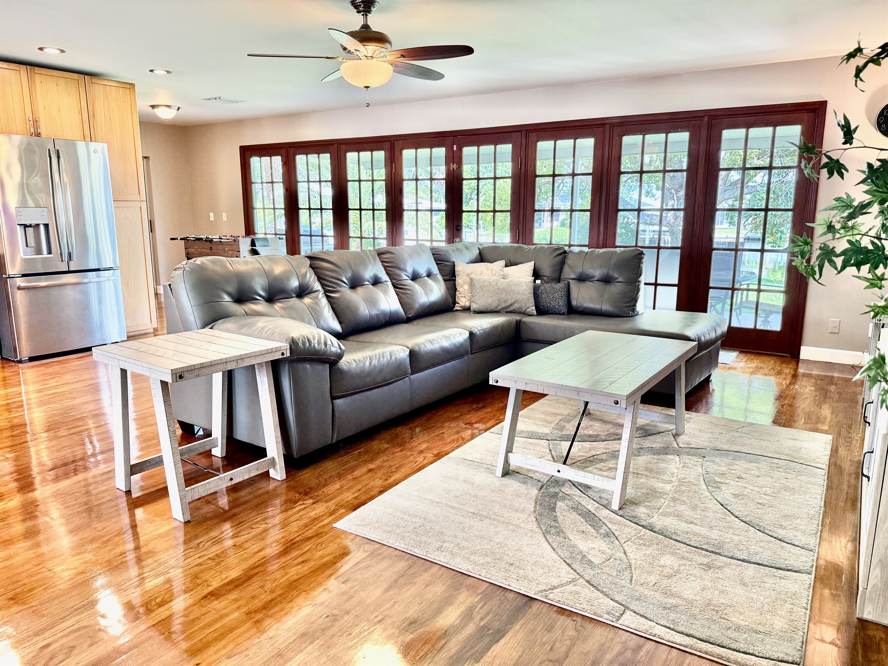 This sun-drenched living room features a plush sectional, modern décor, and sleek hardwood floors—perfect for lounging in style or enjoying a cozy movie night.