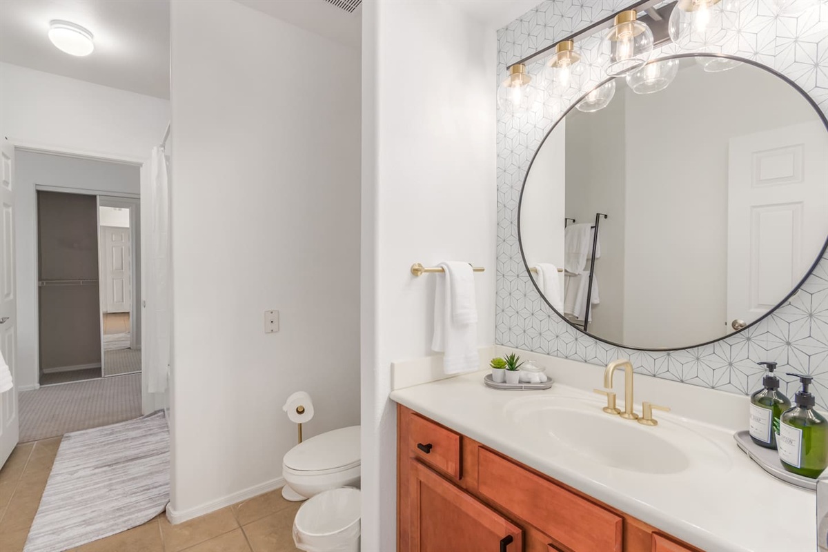 Bathroom with vanity storage, round mirror, bright lighting, and essentials for daily routines.