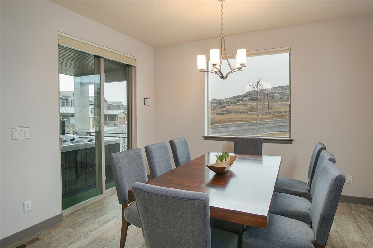 A bright dining area with direct access to the deck with hot tub, offering an elegant setting for meals enhanced by scenic mountain backdrops.
