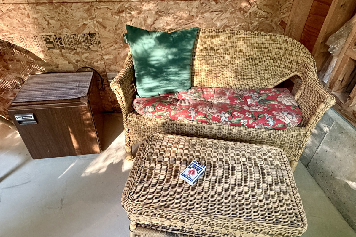 Enjoy a quiet game night in the Settler's Sidecar. This cozy wicker seating nook features a convenient mini-fridge for keeping snacks chilled and a deck of cards ready, providing a perfectly laid-back corner to relax.