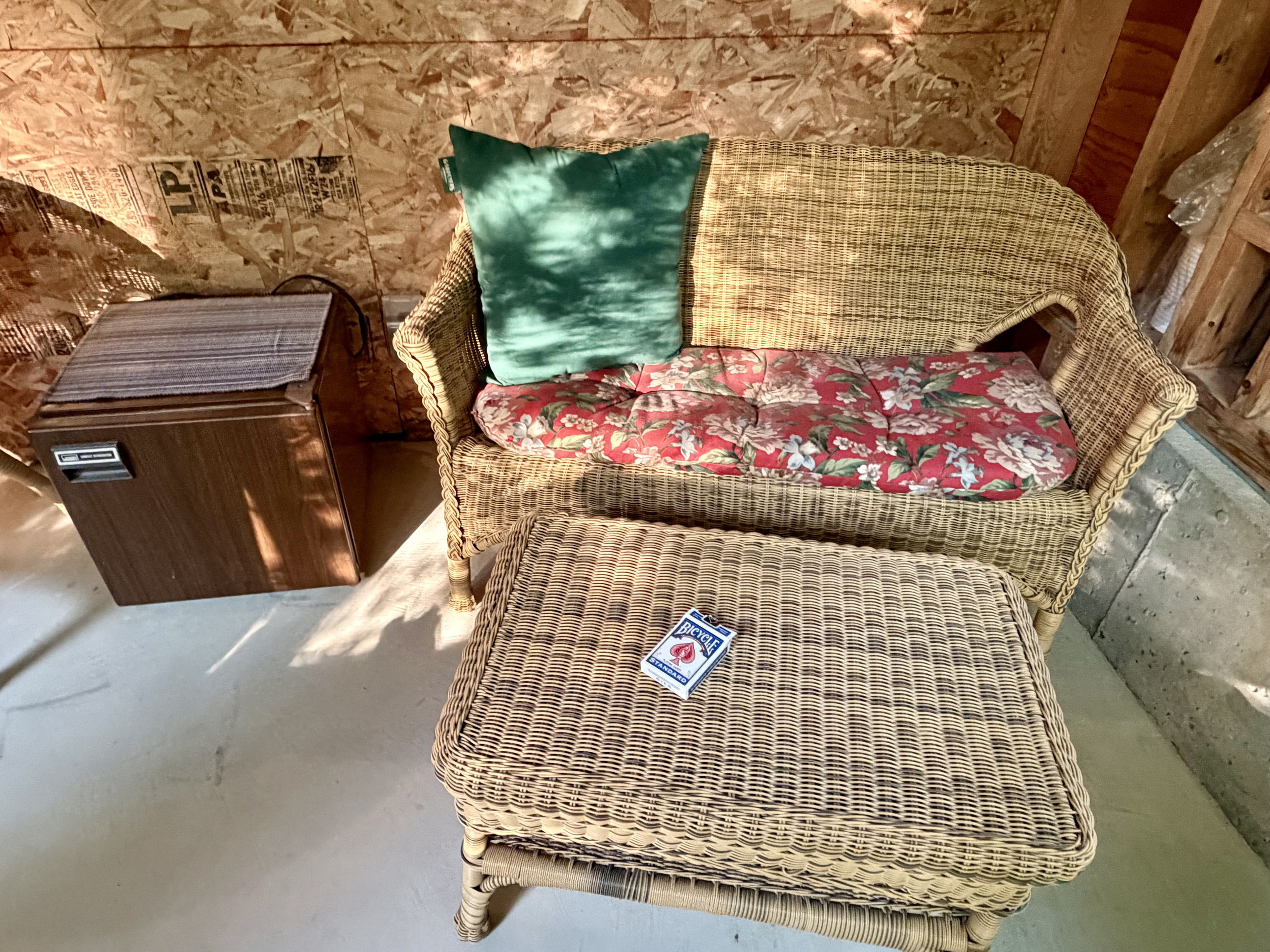 Enjoy a quiet game night in the Settler's Sidecar. This cozy wicker seating nook features a convenient mini-fridge for keeping snacks chilled and a deck of cards ready, providing a perfectly laid-back corner to relax.