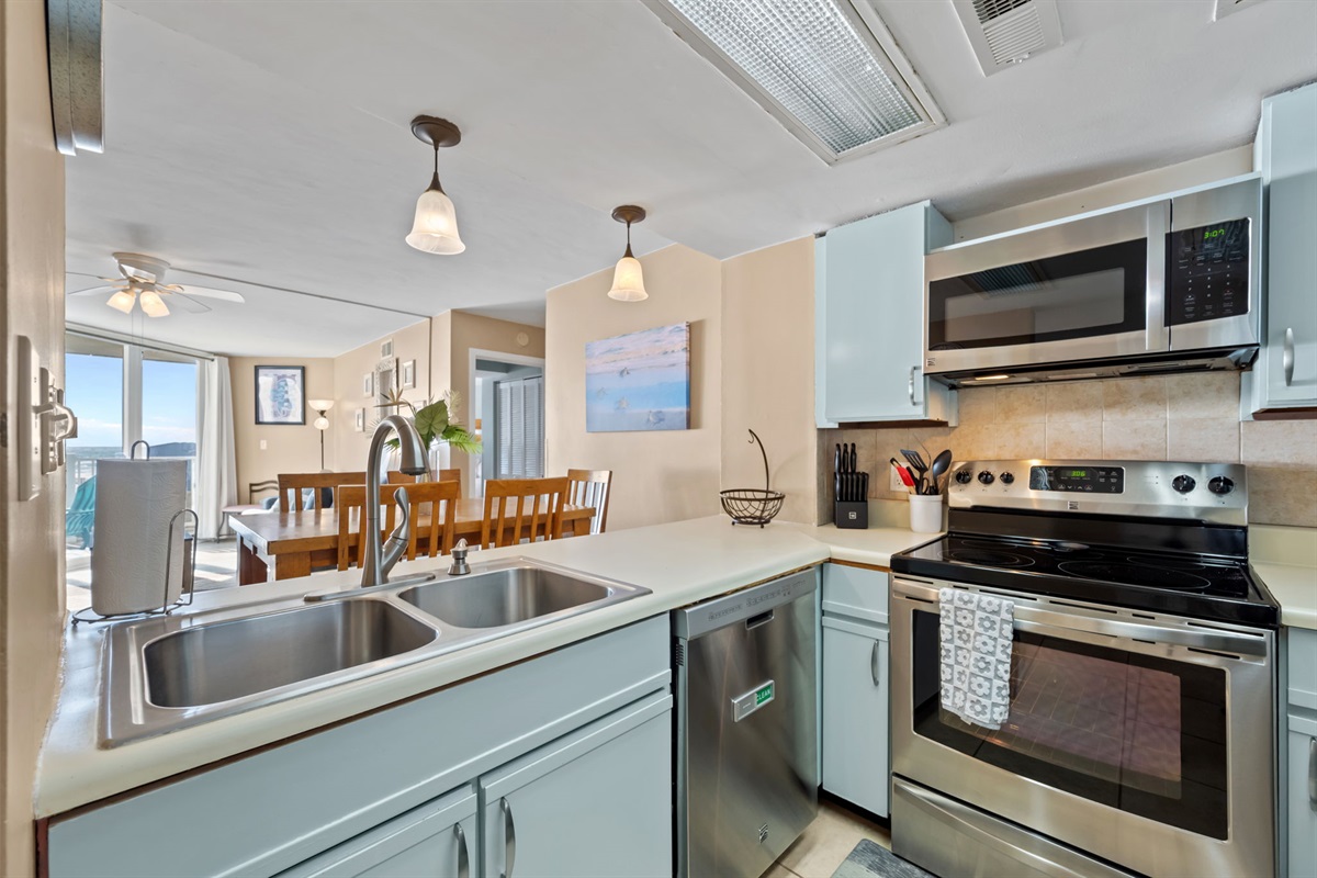Modern, fully equipped kitchen with stainless steel appliances, ample counter space, and open sightlines to the dining and living areas