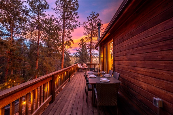 🍽️🌅 Dine on the deck at sunset—string lights ✨, warm cabin glow, and pine-filled views that turn every meal into a moment 🌲🥂