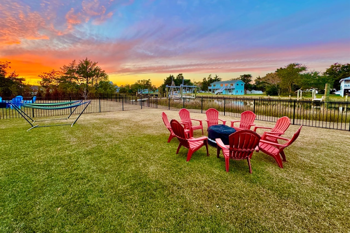 Private backyard dock with boat lift and fillet table, fenced-in backyard, fire pit with Adirondack chairs, hammocks, propane grill, picnic table, outdoor shower, expansive waterfront back deck with table and seating, neighborhood boat ramp and dock