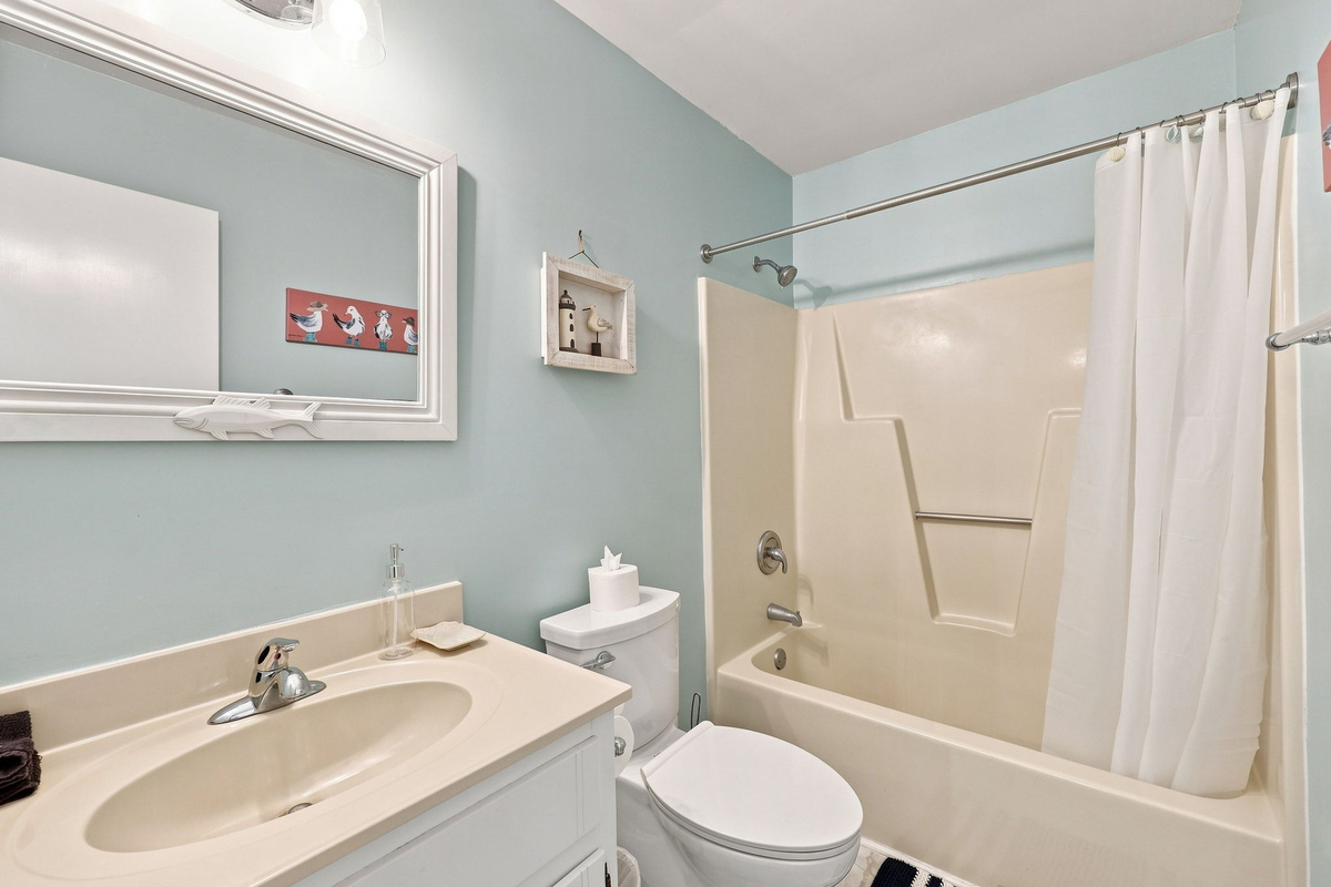 Relax in this soothing light-blue bath featuring cheerful maritime decor and a full tub.