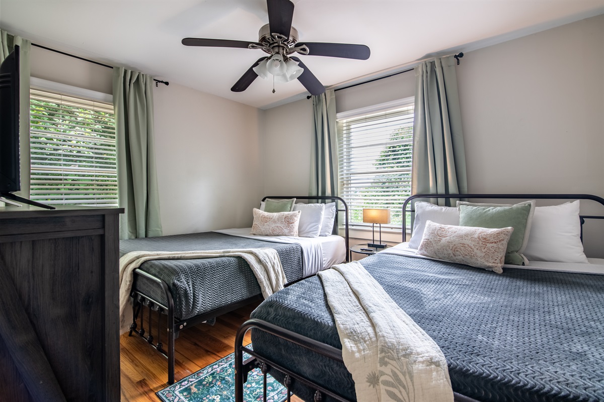 Twin bedroom with cozy bedding and warm sunlight—perfect for guests or family stays.
