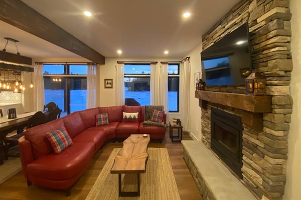 Living room seating in front of wood-burning fireplace and 65 inch smart TV
