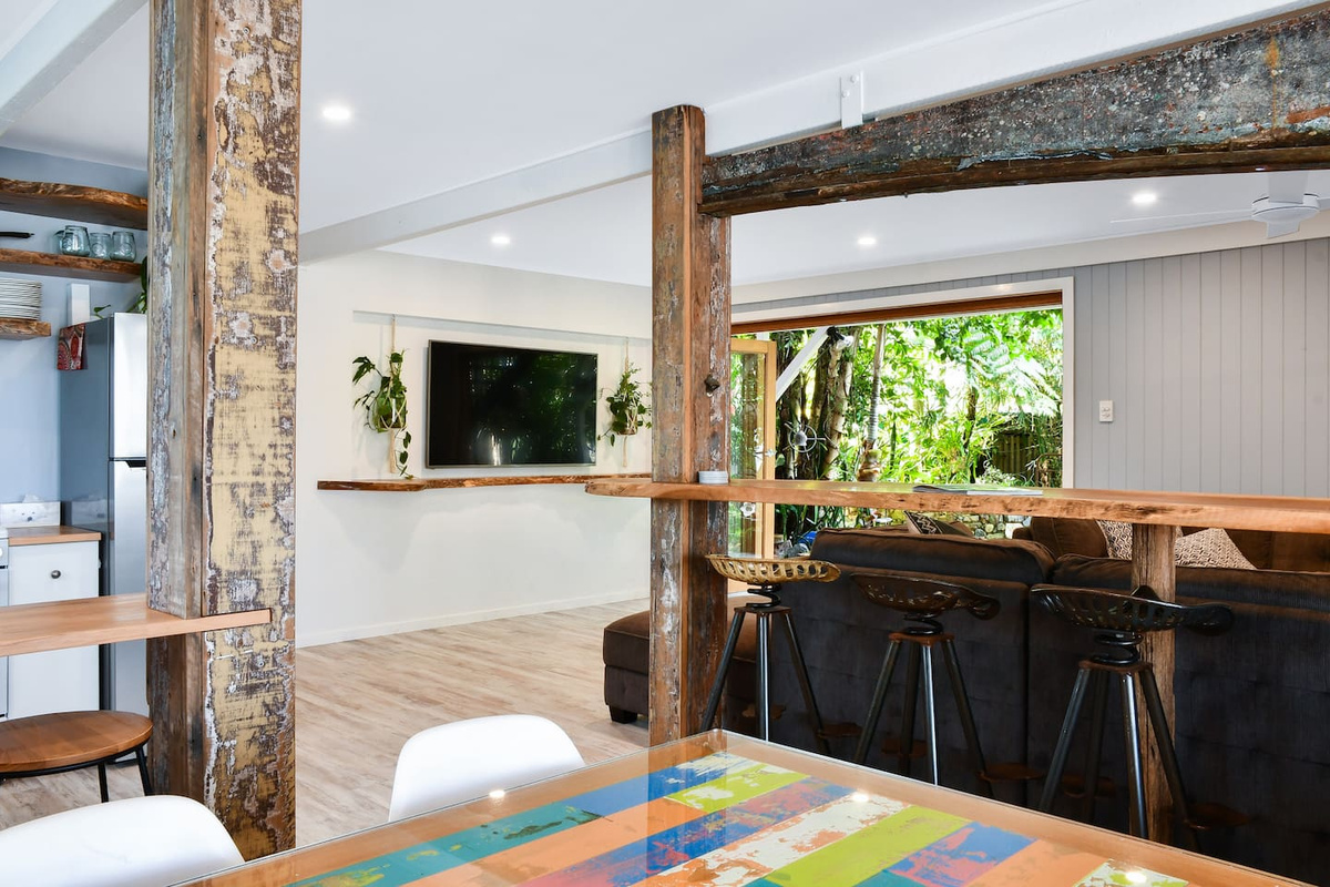 A timber breakfast bar with stools links the living area and adjoining spaces at Aaron's Beachside Boat House, adding another casual seating zone to the ground floor.