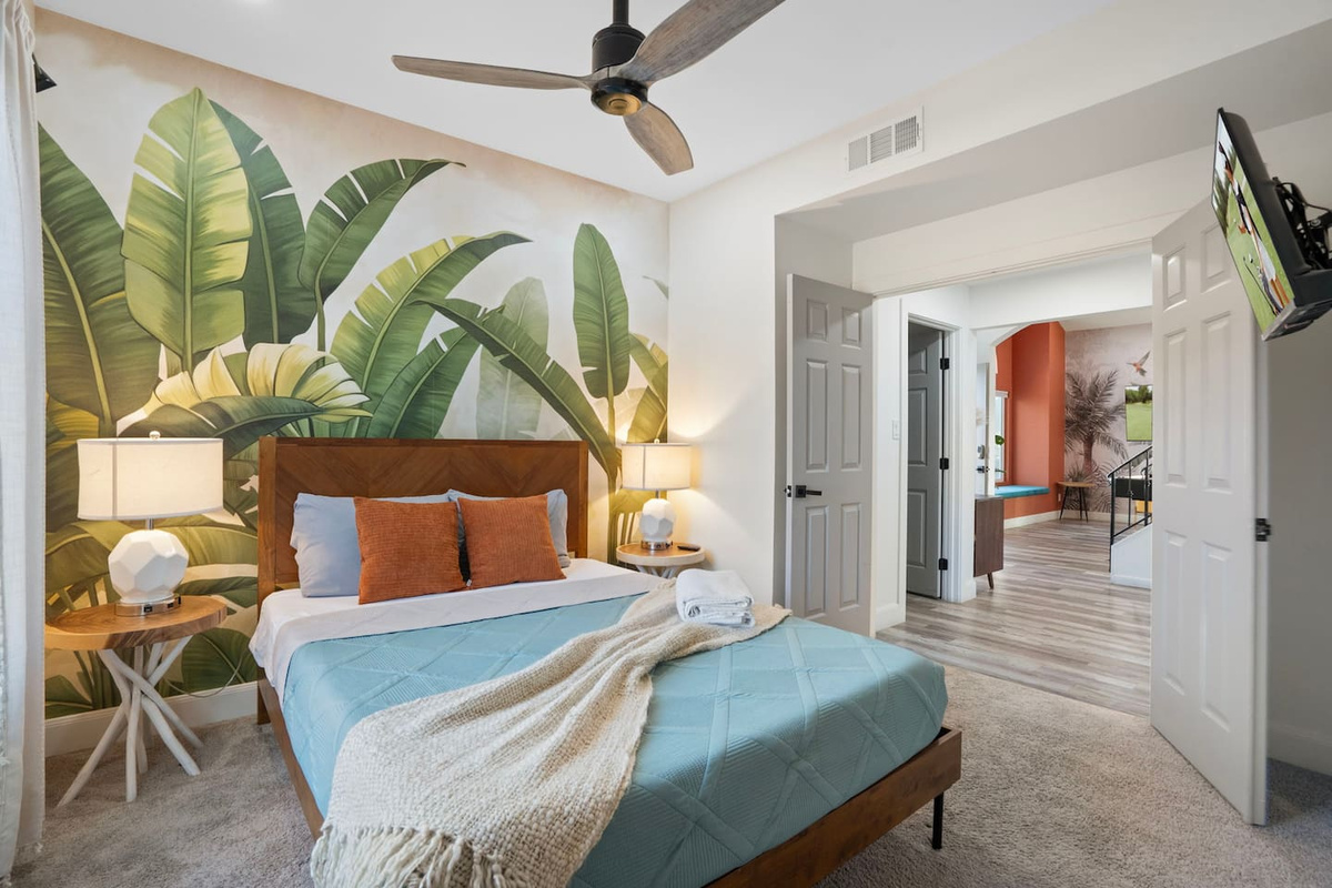 Serene bedroom with oversized tropical mural and easy access to other rooms.