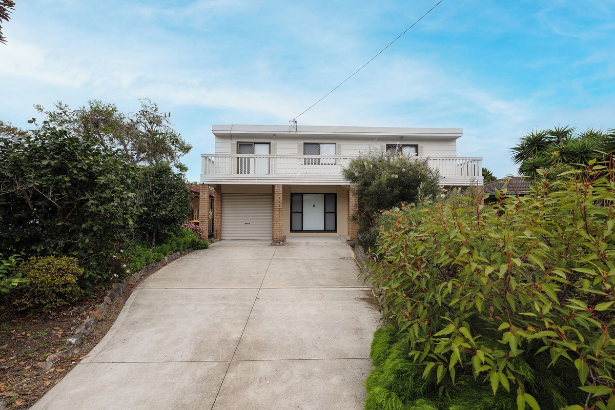 The front exterior at Luna’s Sanctuary shows the driveway, garage, balcony and garden surrounds, giving a clear sense of arrival.