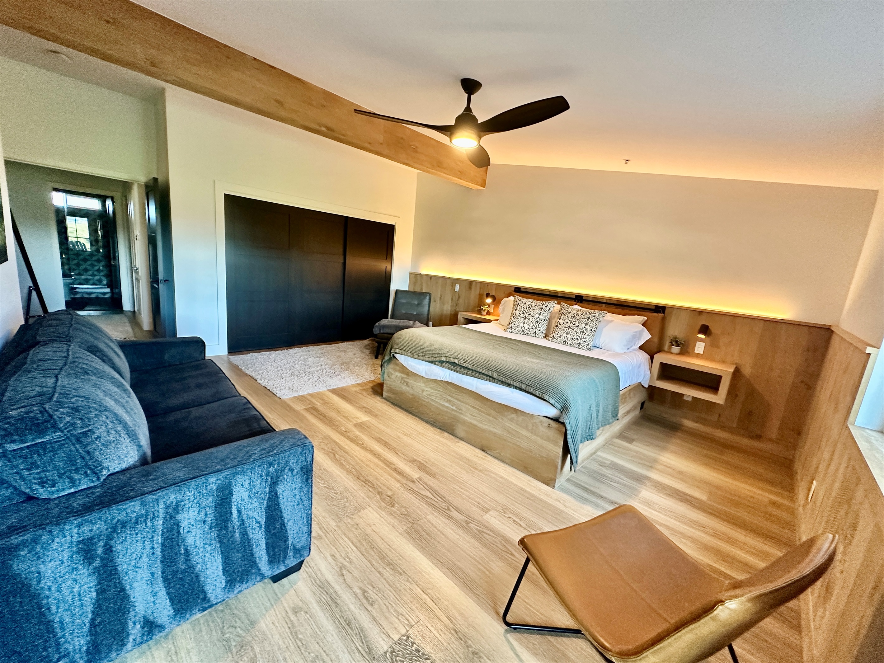 A spacious California King suite featuring a cozy lounge area with a queen pull-out sofa, and a large closet with sleek sliding doors.