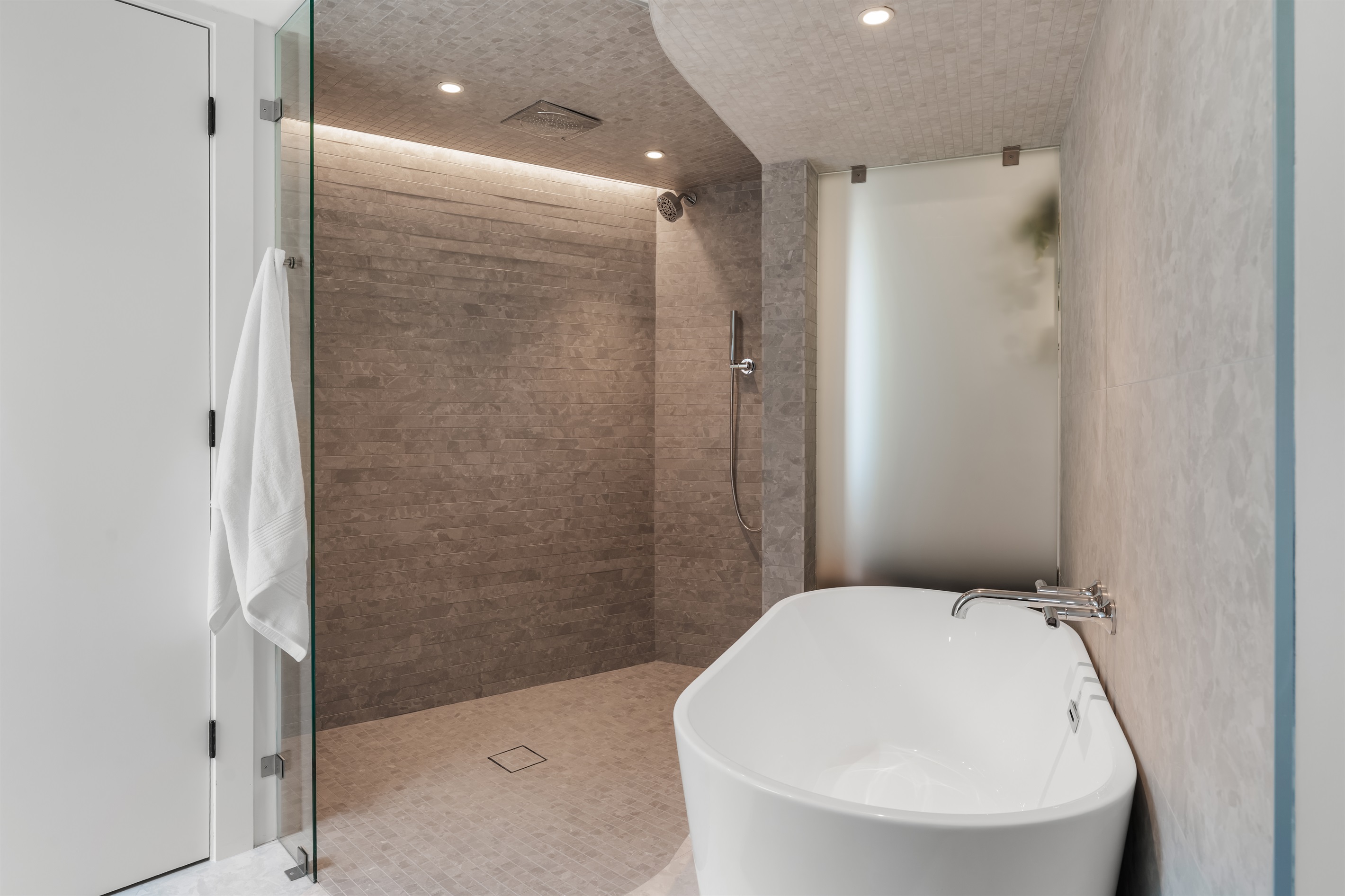 Luxury soaking tub and walk-in shower with serene stone textures—your private retreat to unwind after a long day.