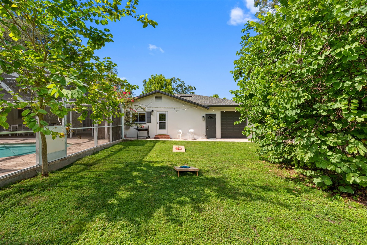 This expansive lawn area surrounds the screened pool, offering plenty of room for play, entertaining, or relaxing under the Florida sunshine.
