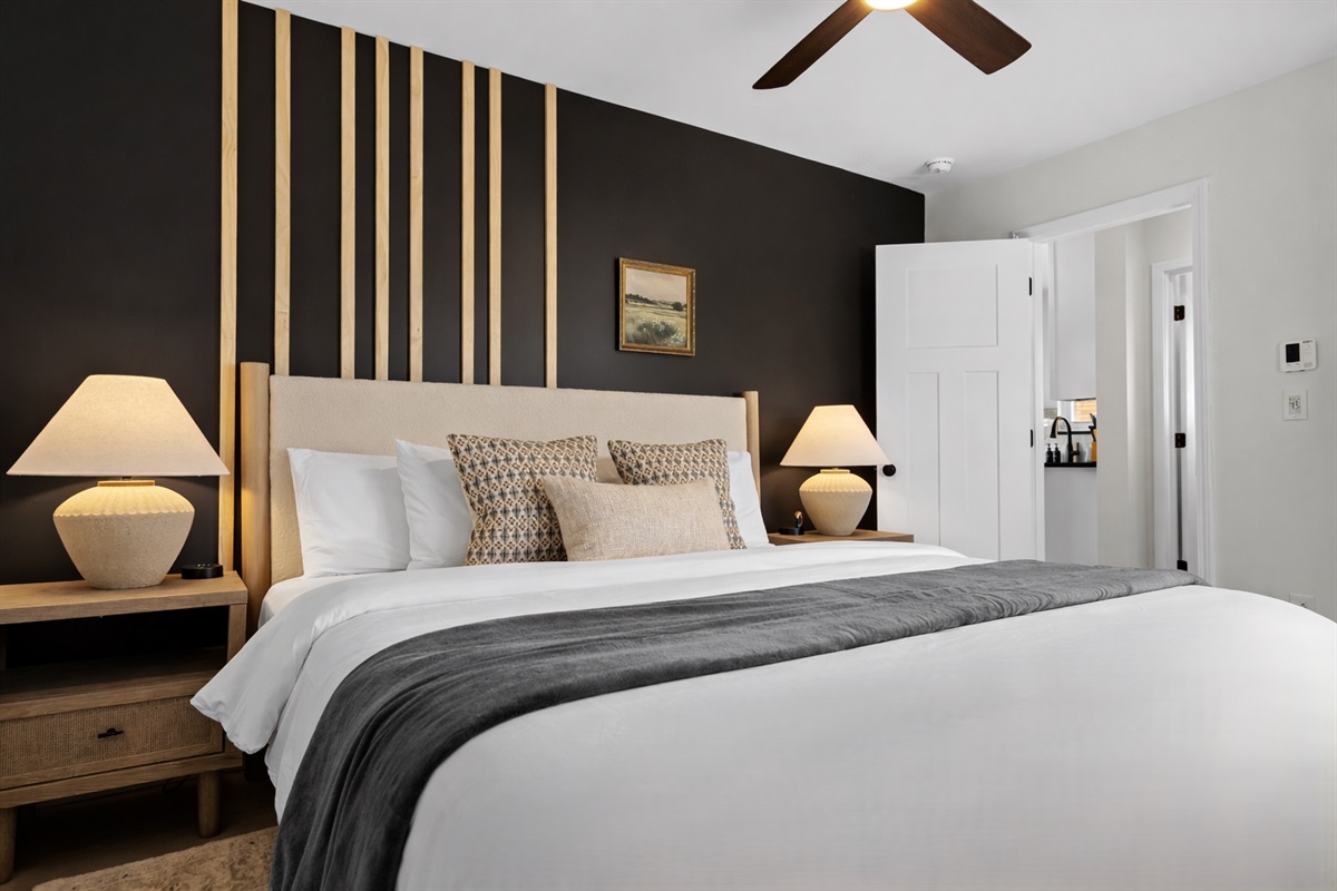 Elegant bedroom with plush king bed, statement accent wall, and warm lighting—crafted for peaceful nights and a relaxing, boutique-style stay.
