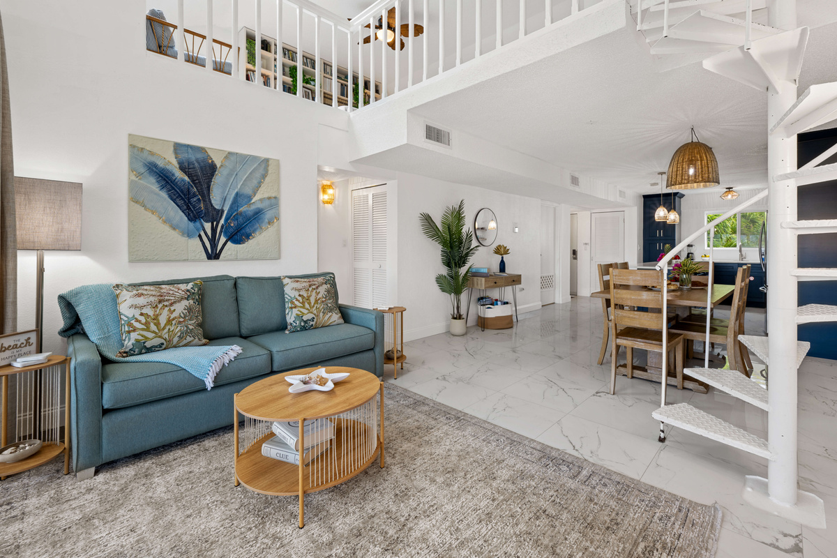 The open-concept living area features soaring ceilings and a charming spiral staircase leading to the loft.