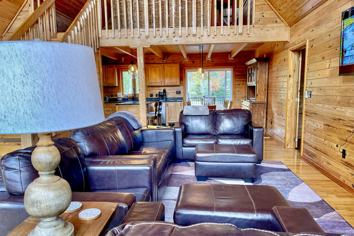 The spacious living room features cathedral ceilings and knotty pine walls, creating a warm, inviting lodge atmosphere perfect for gathering.