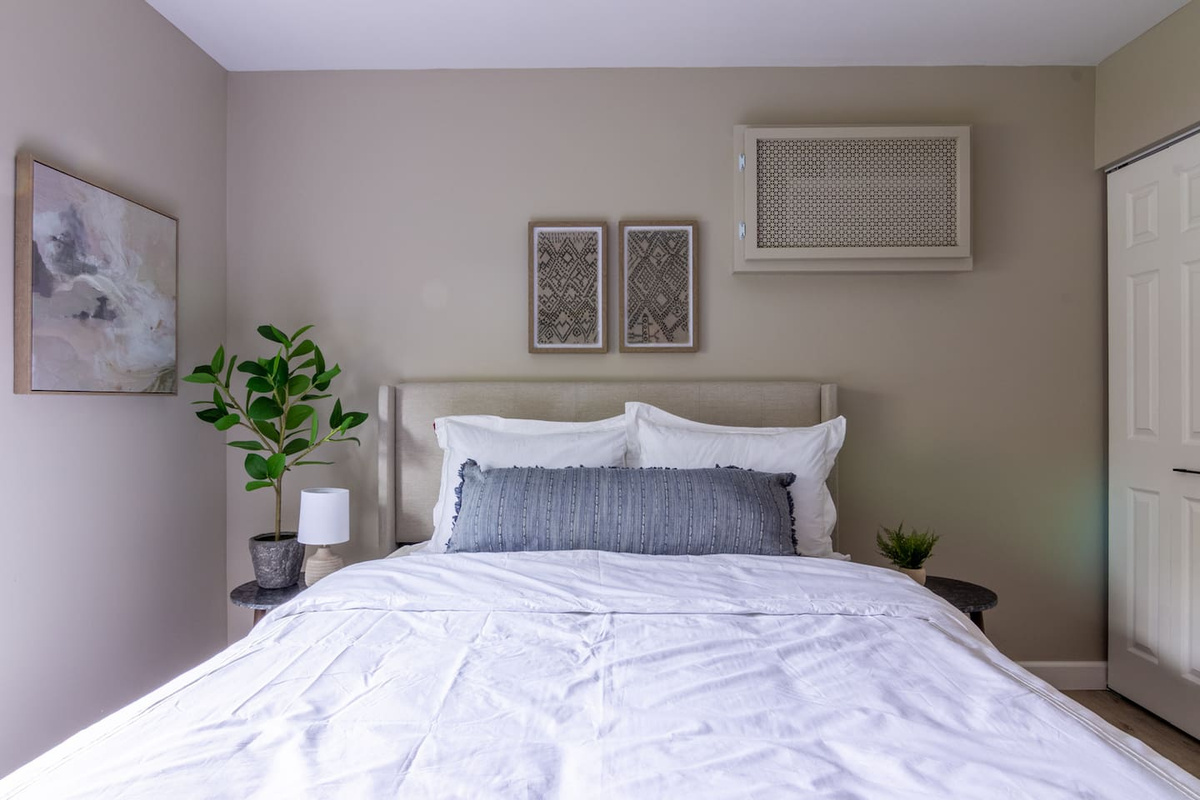 A calm retreat with layered linens and a plush upholstered headboard, ready for slow mornings.