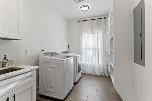 Extra large washer and dryer, laundry and cleaning supplies, sink, and pool towels.