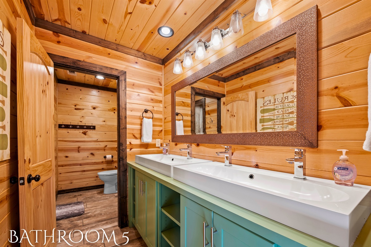 A uniquely designed bathroom features a long white countertop with dual sinks over a teal vanity