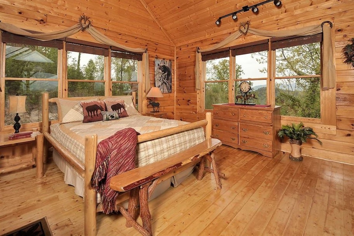 - Peaceful bedroom with handcrafted log furniture and soft natural light   - Surrounded by windows framing the lush forest and distant peaks   - Perfect setting for restful nights and rejuvenating mountain mornings