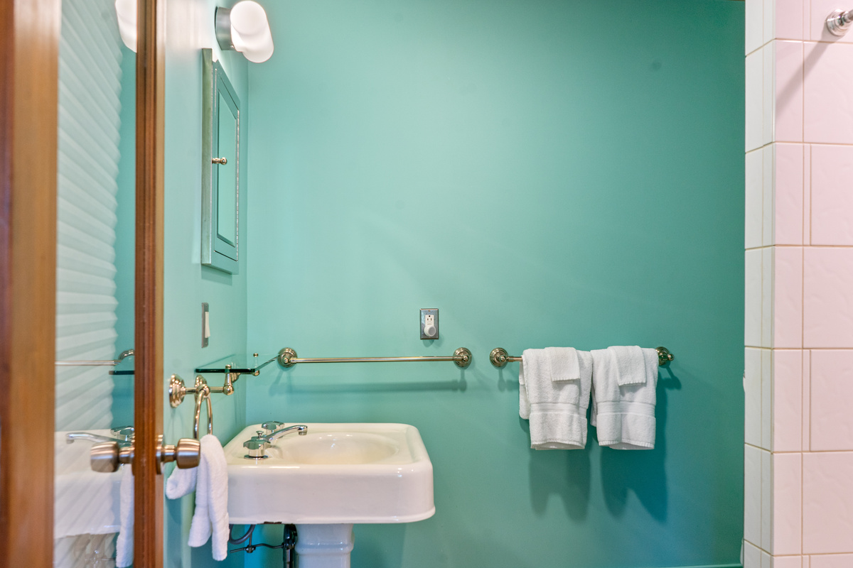 The dedicated full bathroom serving "The Crag's" Base Camp. Features a vintage pedestal sink, polished chrome fixtures, crisp tile, and fresh plush towels—offering complete comfort for guests on the ground floor.