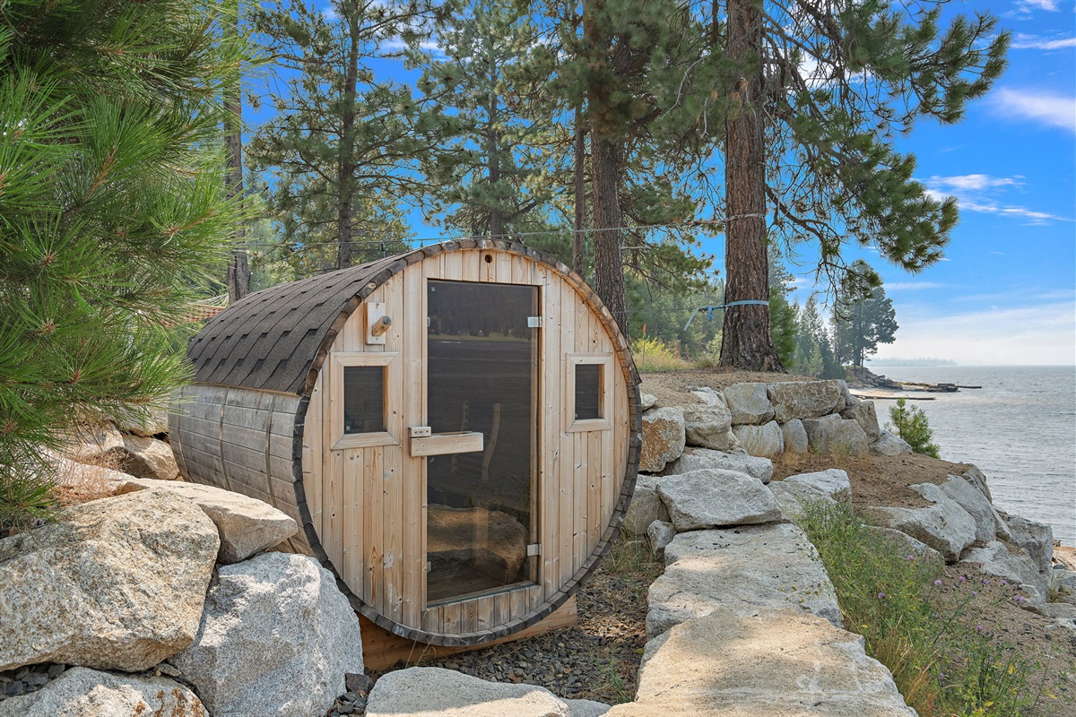 Lakeside barrel sauna offers forest views and peaceful waters.