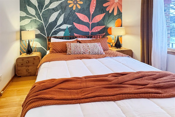 Wake up to art: statement wall mural, plush king bed, and velvet drapery.