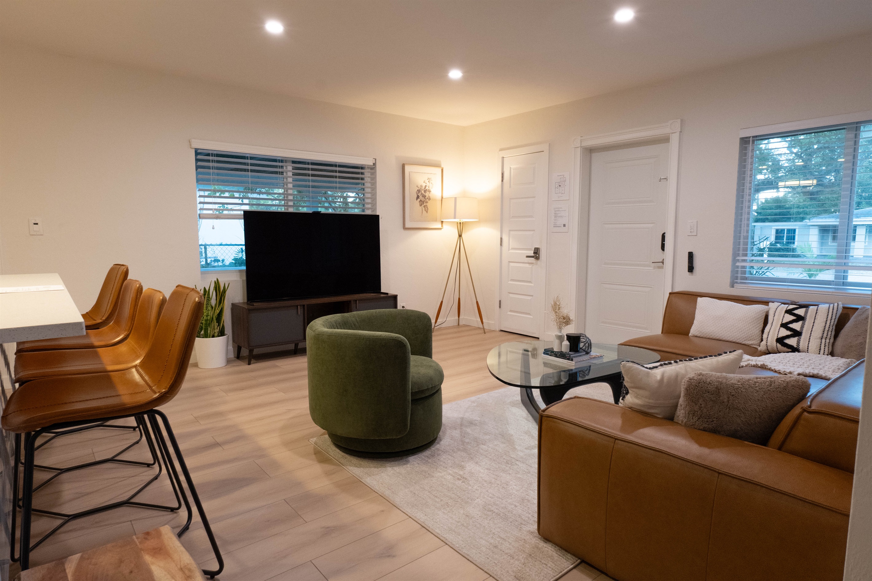 Living room with large TV, natural light, and comfortable seating for groups