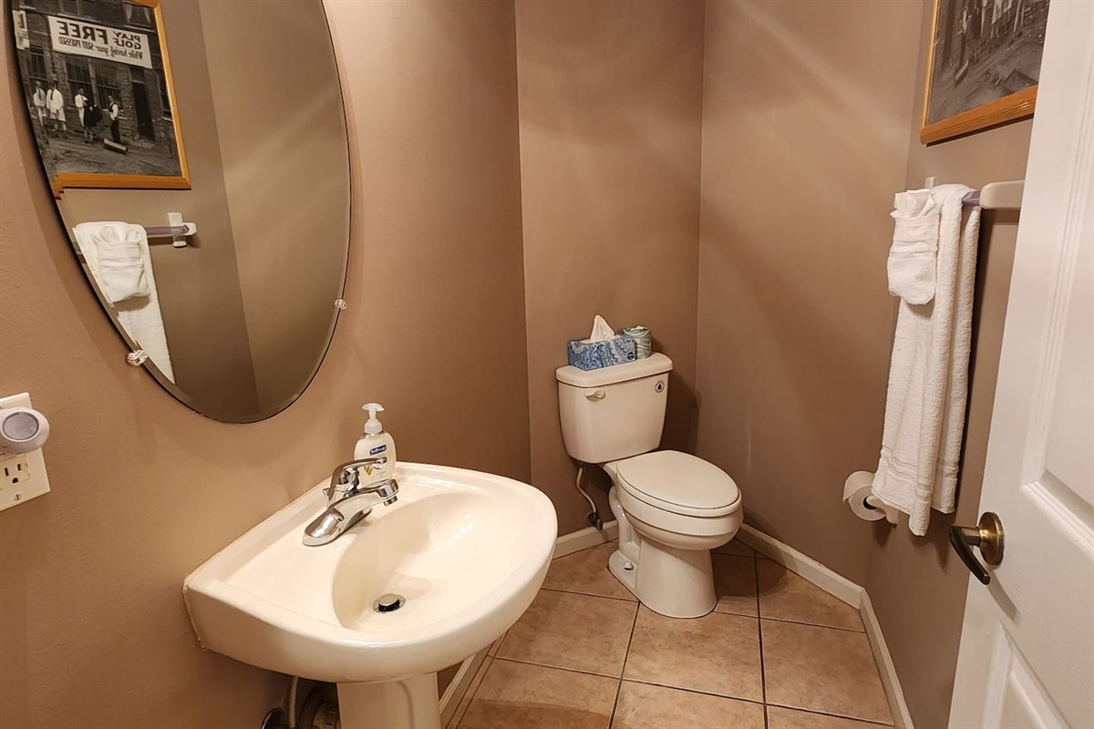 Convenient half bathroom with pedestal sink, tile flooring, and neutral decor.