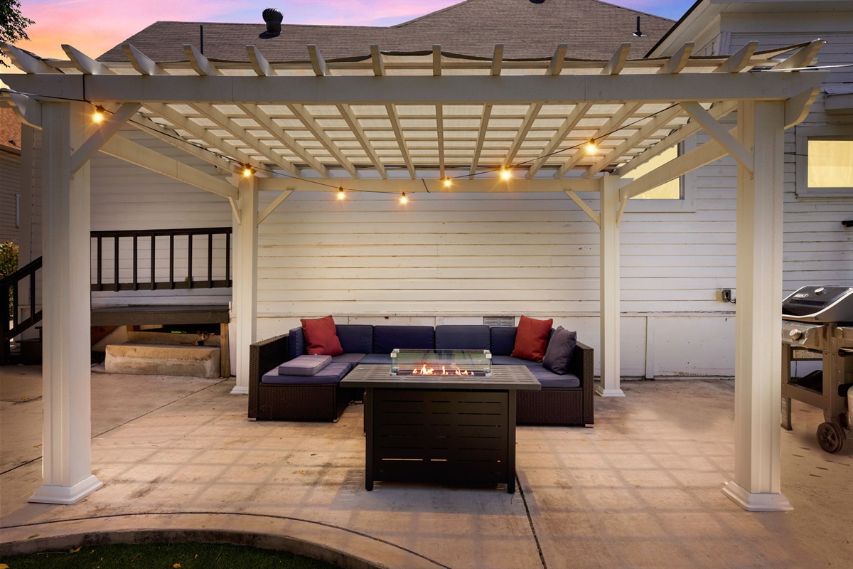 The outdoor lighting creates a magical ambiance, accentuating the lush green lawn and large patio, making it the perfect spot for barbecues or late-night conversations. 