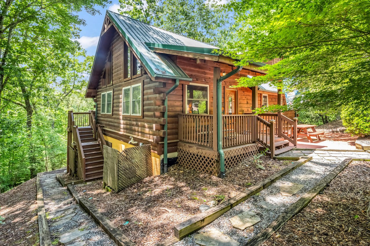 Front and side view of the cabin surrounded by mature trees